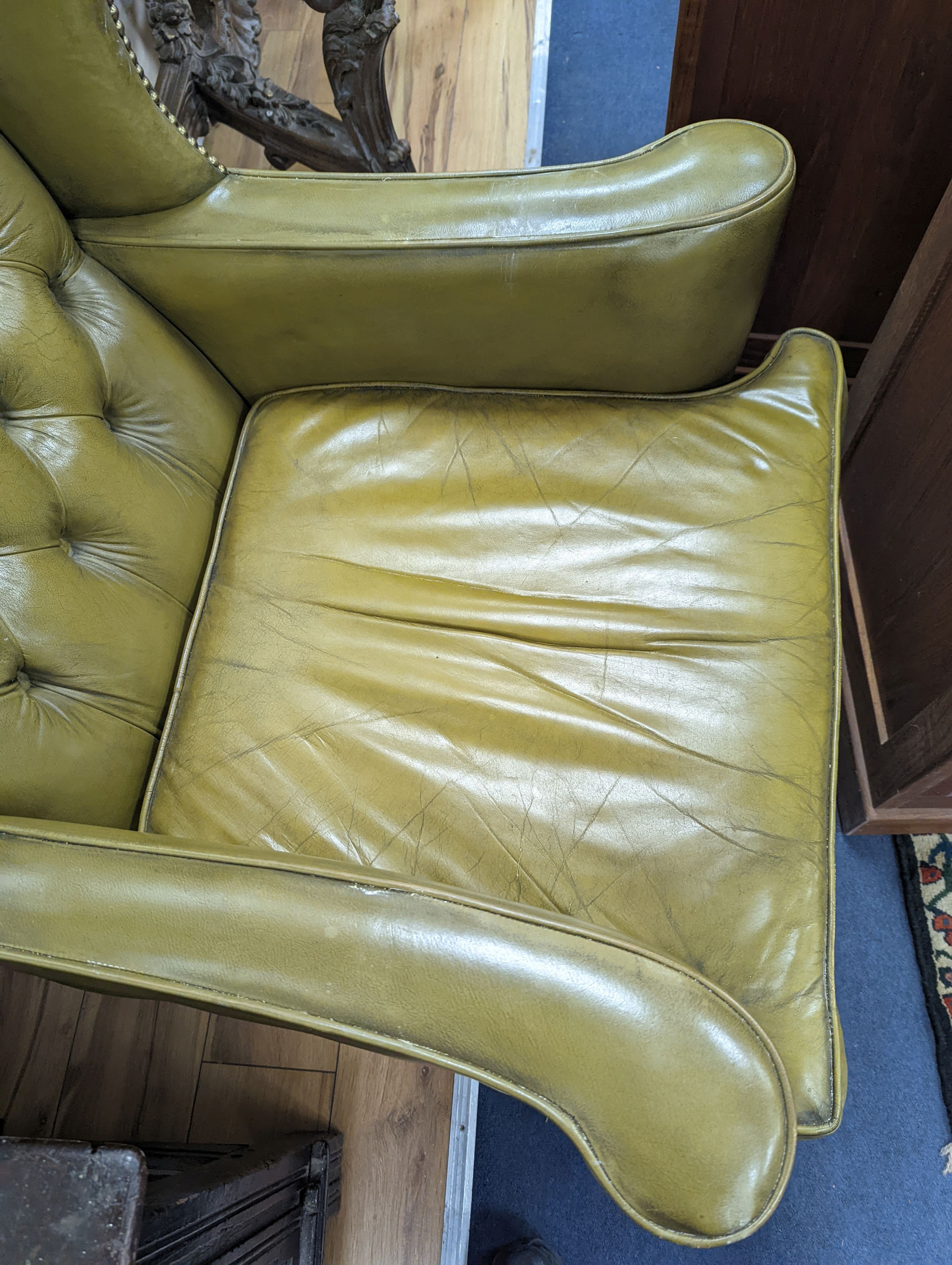 A George III style wing armchair upholstered in studded buttoned green leather, width 79cm, depth 76cm, height 116cm